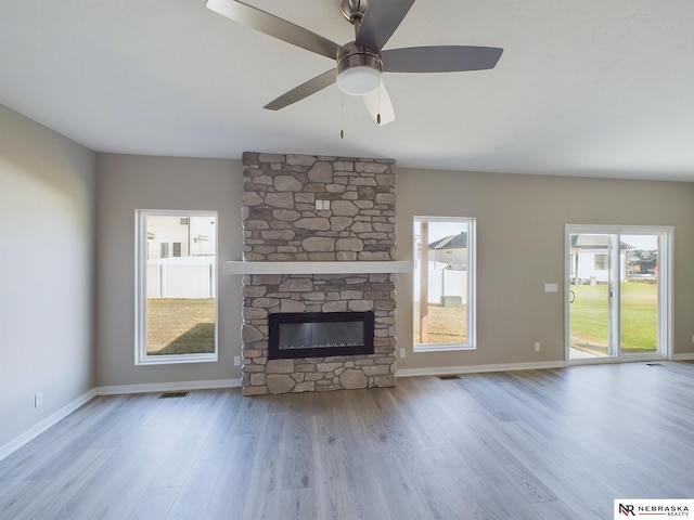 unfurnished living room featuring ceiling fan, a fireplace, and a wealth of natural light