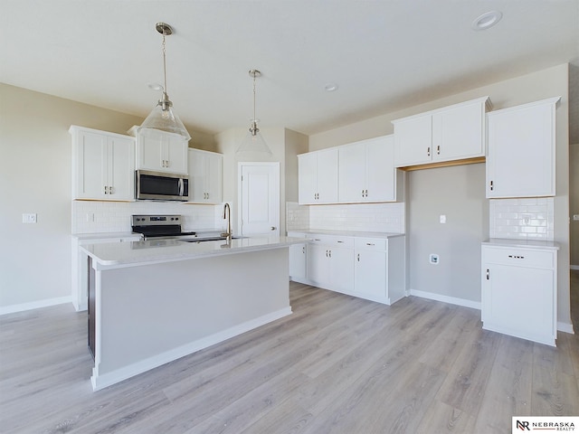 kitchen with a kitchen island with sink, white cabinets, stainless steel appliances, and light wood-type flooring