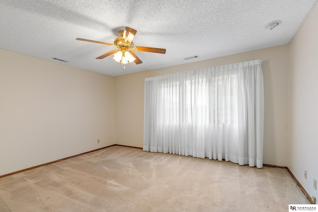 unfurnished room with a textured ceiling, ceiling fan, and light carpet