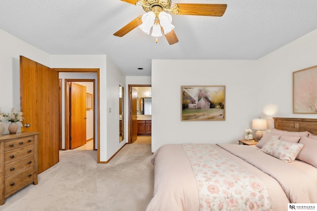 bedroom featuring ensuite bathroom, ceiling fan, light colored carpet, and a textured ceiling