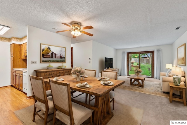 dining room featuring ceiling fan, a textured ceiling, and light wood-type flooring