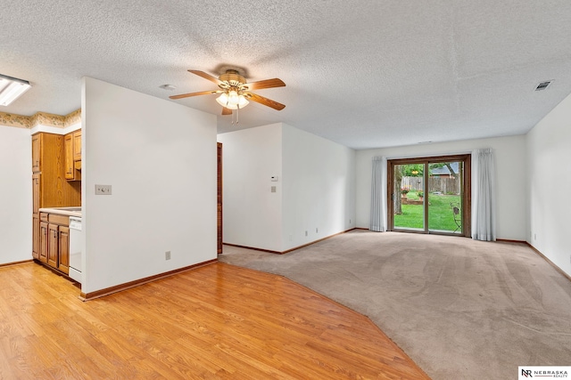 unfurnished living room featuring a textured ceiling, ceiling fan, and light carpet