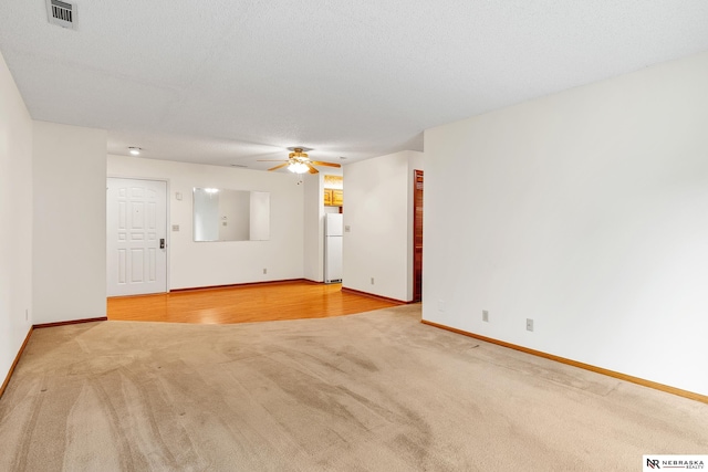 empty room featuring ceiling fan, light colored carpet, and a textured ceiling