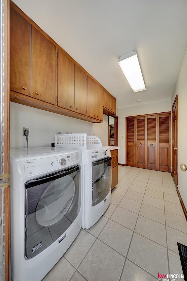 laundry room featuring light tile patterned floors, independent washer and dryer, and cabinets