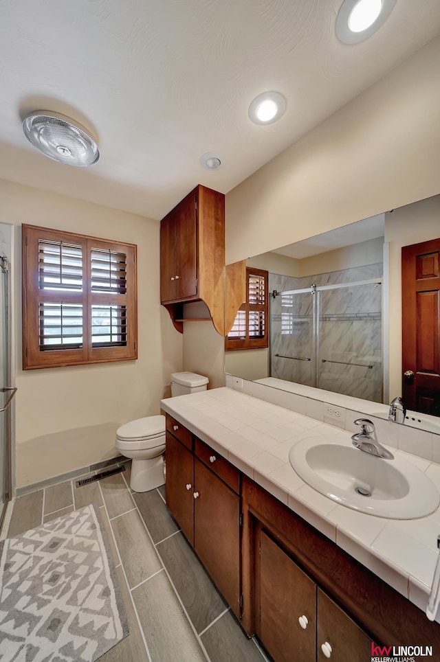 bathroom with vanity, toilet, tile patterned flooring, and an enclosed shower