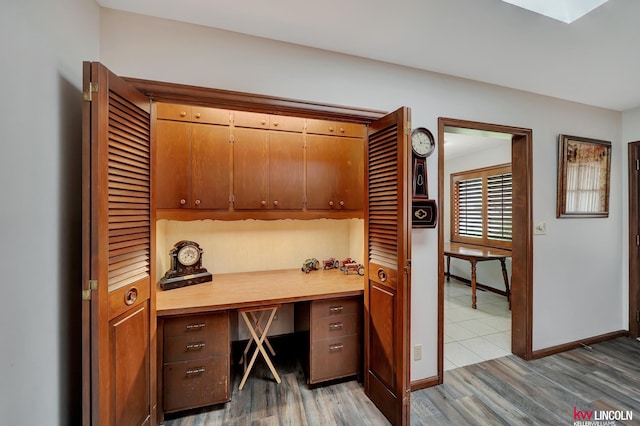 home office with built in desk and hardwood / wood-style floors