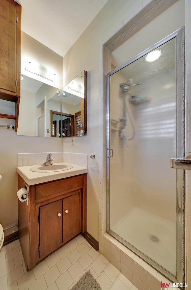 bathroom with vanity, toilet, tile patterned flooring, and walk in shower