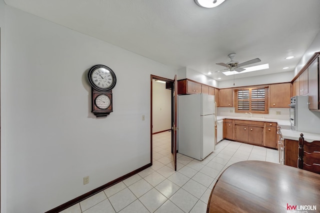 kitchen with light tile patterned floors, white fridge, sink, and ceiling fan