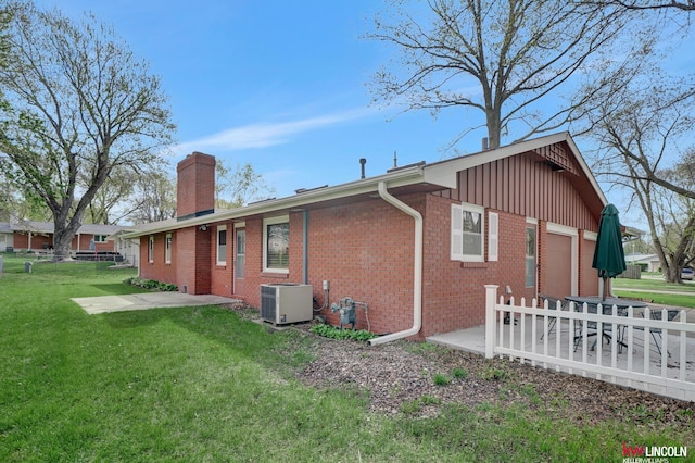 exterior space with a garage, a yard, and cooling unit