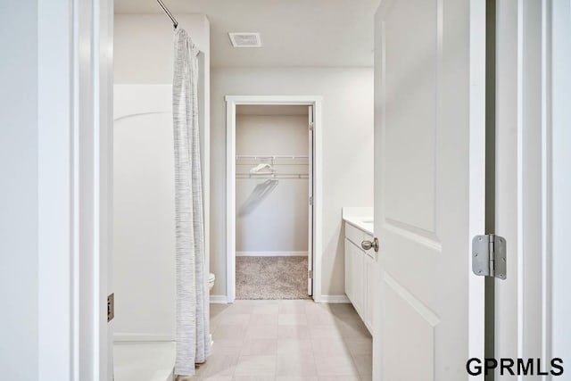 bathroom with walk in shower, vanity, and toilet