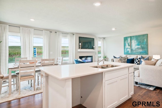 kitchen with a kitchen island with sink, sink, white cabinetry, and dark wood-type flooring