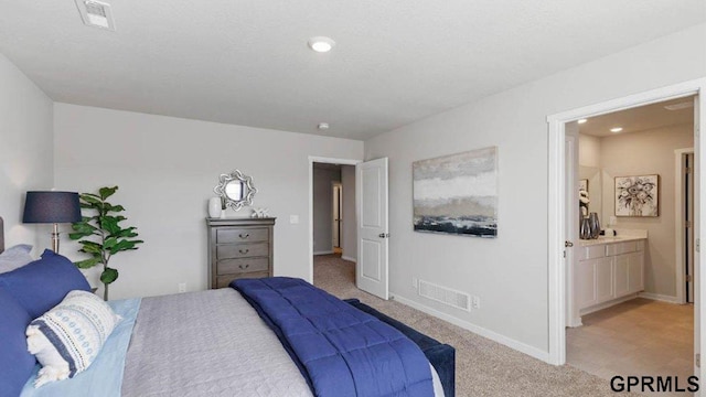 bedroom with light carpet and ensuite bath