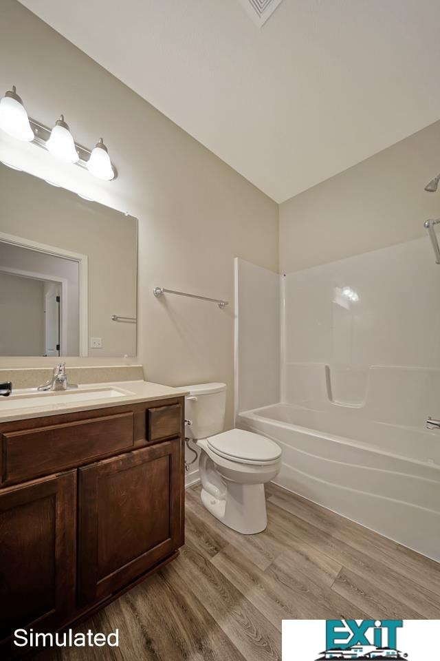 full bathroom featuring vanity, vaulted ceiling, shower / tub combination, toilet, and hardwood / wood-style flooring