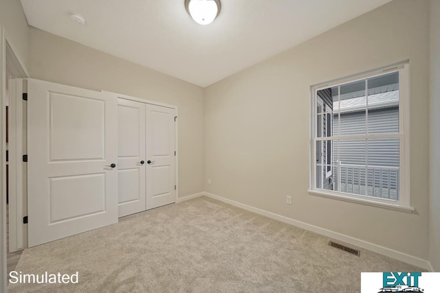 unfurnished bedroom with a closet and light carpet