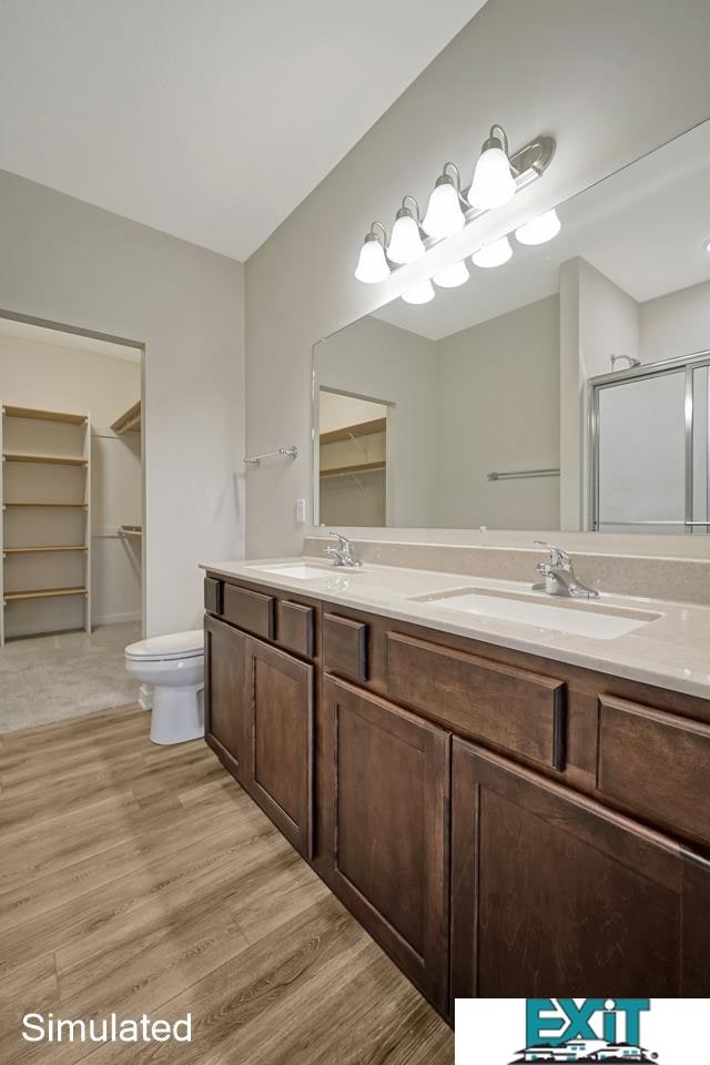 bathroom with an enclosed shower, wood-type flooring, toilet, and vanity