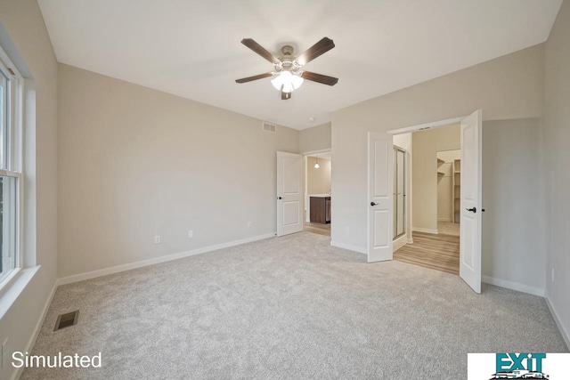 unfurnished bedroom with light colored carpet, ceiling fan, a walk in closet, and a closet