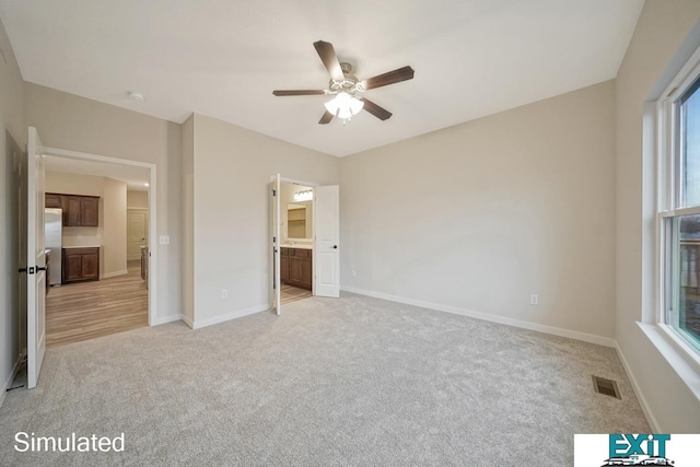 unfurnished bedroom featuring ceiling fan, light carpet, and ensuite bath