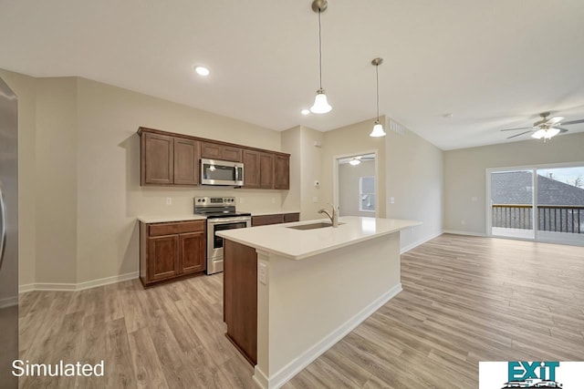 kitchen with light hardwood / wood-style flooring, stainless steel appliances, sink, ceiling fan, and an island with sink