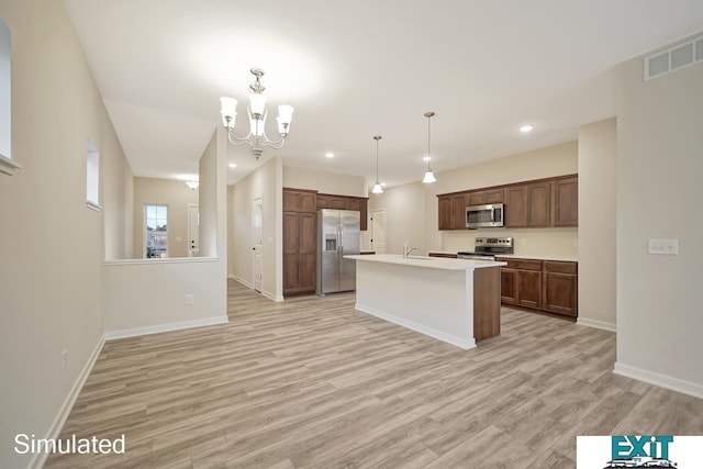 kitchen with appliances with stainless steel finishes, light hardwood / wood-style floors, a center island with sink, and hanging light fixtures