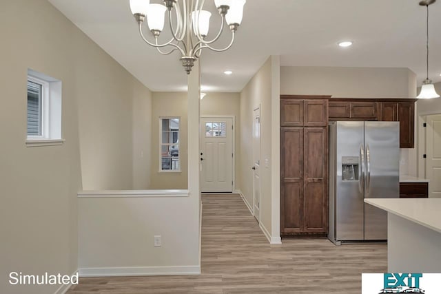 kitchen featuring light wood-type flooring, pendant lighting, an inviting chandelier, and stainless steel fridge with ice dispenser