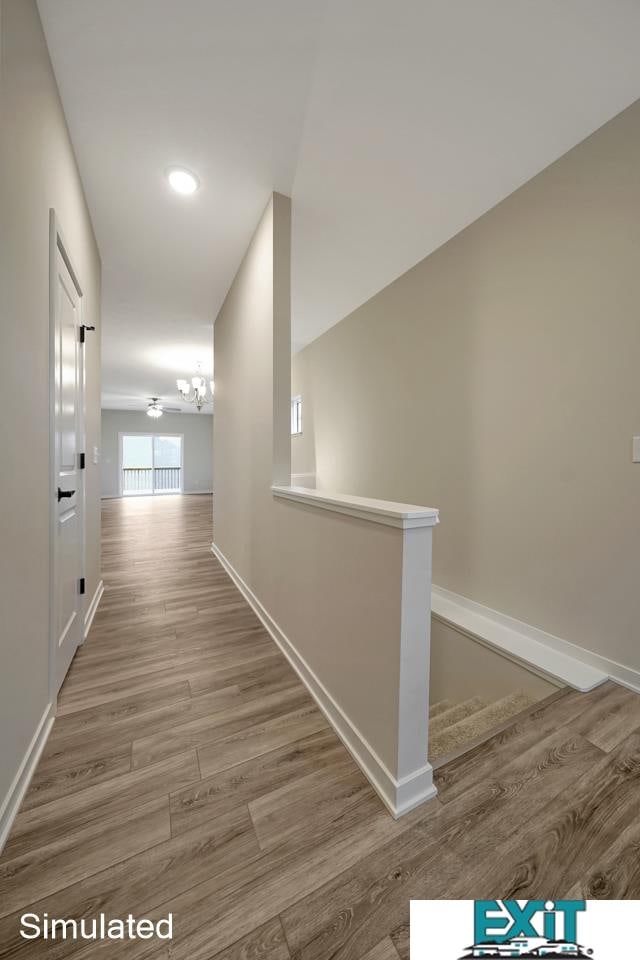 corridor featuring wood-type flooring and an inviting chandelier