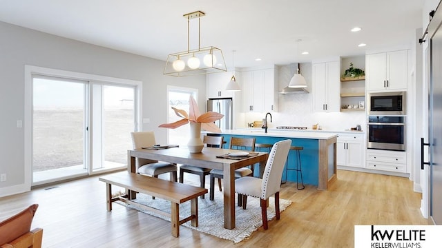 dining space featuring a barn door, recessed lighting, visible vents, and light wood-style floors