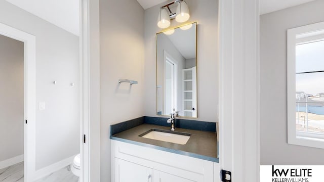 bathroom featuring vanity, toilet, and baseboards