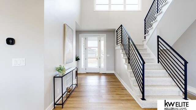 foyer with light hardwood / wood-style flooring and a towering ceiling