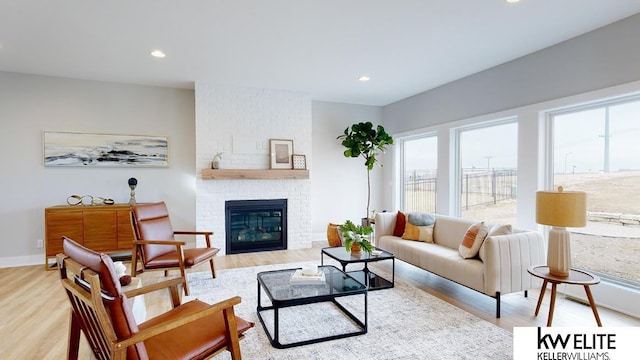 living room featuring a brick fireplace, wood finished floors, and recessed lighting