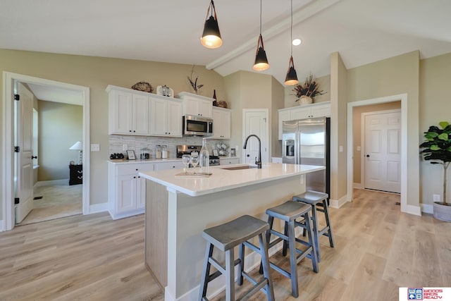 kitchen with white cabinets, stainless steel appliances, and lofted ceiling with beams