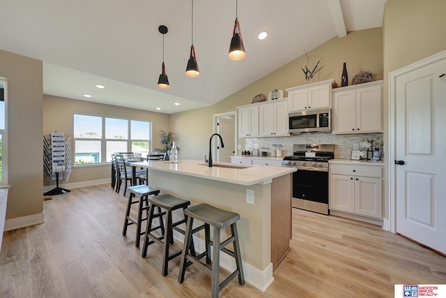 kitchen with stainless steel appliances, white cabinetry, decorative light fixtures, and sink