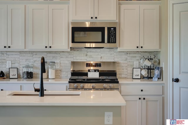 kitchen featuring white cabinets, appliances with stainless steel finishes, backsplash, and sink