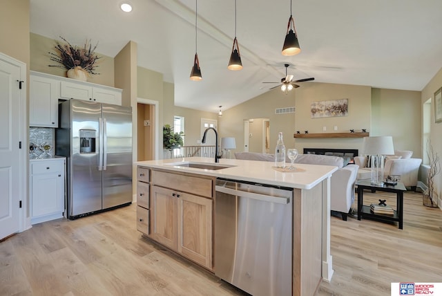 kitchen featuring stainless steel appliances, lofted ceiling, ceiling fan, a kitchen island with sink, and sink