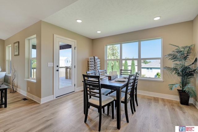 dining room featuring light wood-type flooring and a textured ceiling