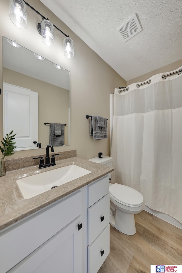 bathroom with vanity, toilet, curtained shower, a textured ceiling, and hardwood / wood-style floors