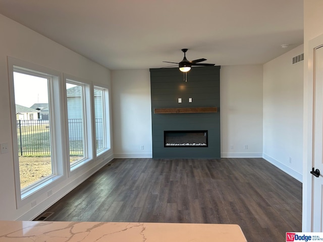 unfurnished living room with dark hardwood / wood-style flooring, ceiling fan, and a large fireplace