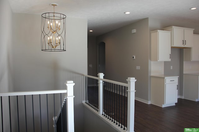 corridor with dark hardwood / wood-style flooring and an inviting chandelier