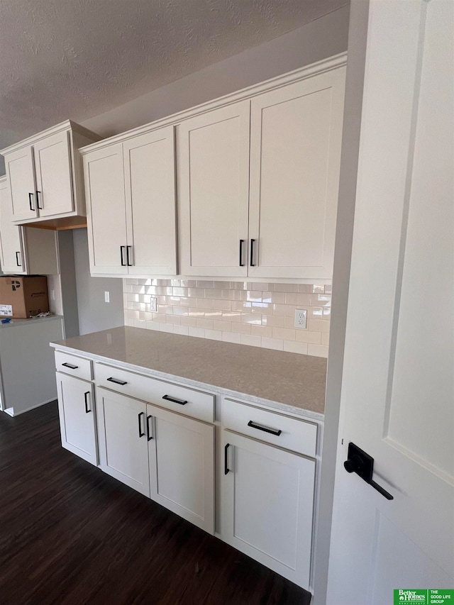 kitchen with a textured ceiling, white cabinetry, backsplash, and dark hardwood / wood-style floors