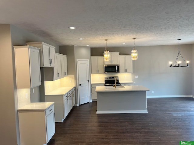 kitchen with white cabinets, dark hardwood / wood-style flooring, a kitchen island with sink, stainless steel appliances, and pendant lighting