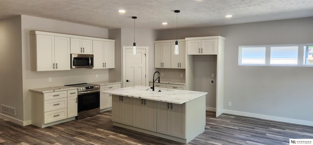 kitchen featuring appliances with stainless steel finishes, dark hardwood / wood-style floors, hanging light fixtures, a center island with sink, and white cabinets