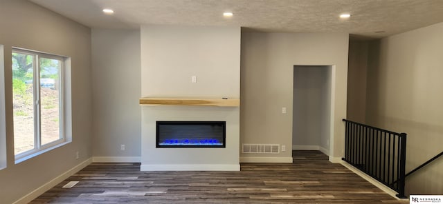 unfurnished living room featuring dark hardwood / wood-style flooring and a textured ceiling