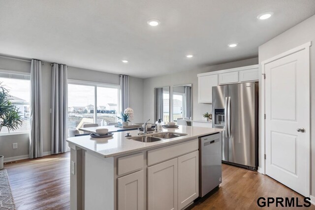 kitchen with hardwood / wood-style floors, sink, stainless steel appliances, and a center island with sink