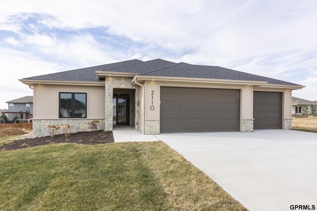 prairie-style home featuring a front lawn and a garage