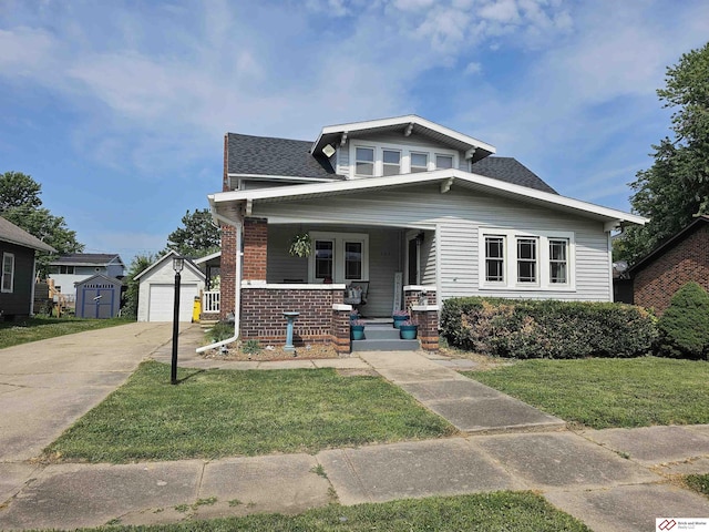 bungalow-style house featuring an outbuilding, brick siding, covered porch, a front yard, and driveway