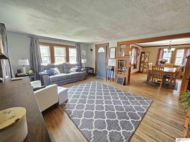 living room featuring a textured ceiling, a chandelier, a wealth of natural light, and wood finished floors