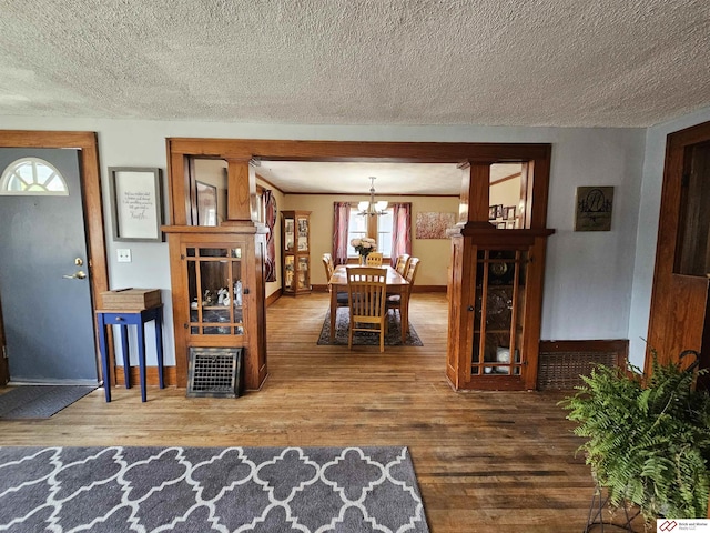 dining space featuring a notable chandelier, a textured ceiling, baseboards, and wood finished floors