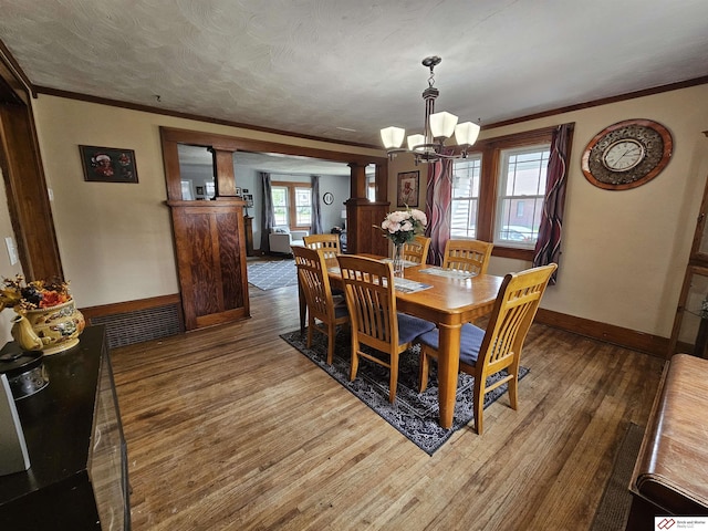 dining area with a chandelier, visible vents, crown molding, and wood finished floors