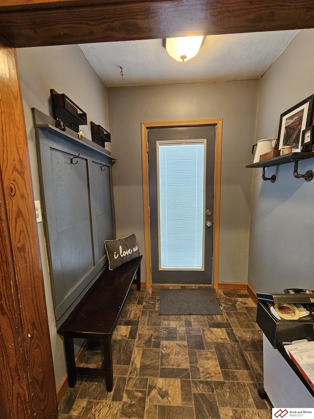 mudroom featuring stone finish floor and baseboards