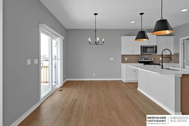 kitchen featuring a wealth of natural light, appliances with stainless steel finishes, tasteful backsplash, and light wood-type flooring