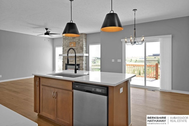 kitchen with stainless steel dishwasher, sink, light hardwood / wood-style flooring, and a center island with sink